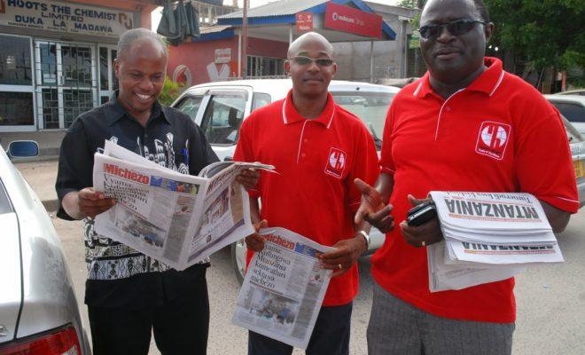 Ansbert Ngurumo (left) reads one of the newspapers he previously edited. Credit: John Dande.