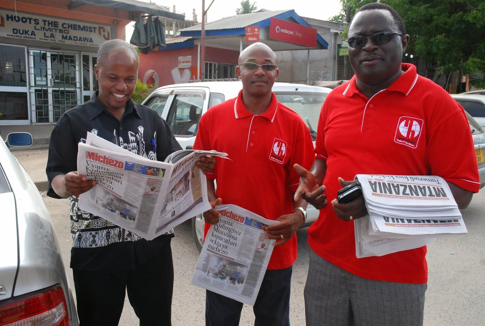 Ansbert Ngurumo (left) reads one of the newspapers he previously edited. Credit: John Dande.