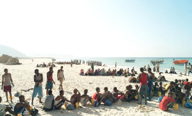 Refugees and migrants line up on a Somalia beach to board the boats that will take them across the Gulf of Aden to Yemen. In a military style operation, the passengers board the small smugglers’ boats in groups of 10. The overcrowded boats can take days to cross. Credit: Alixandra Fazzina.