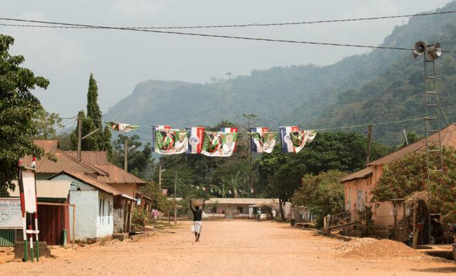 A woman walks under election banner during the 2016 Ghana Elections in the Volta region. Credit: Carsten ten Brink.