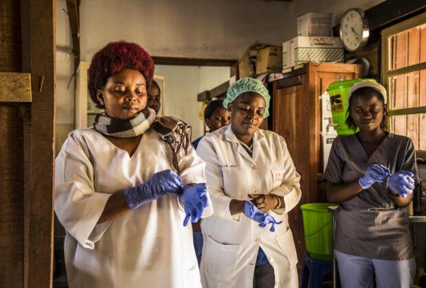 Abuja Declaration. Health workers in the DRC put on gloves on before checking patients at the hospital.