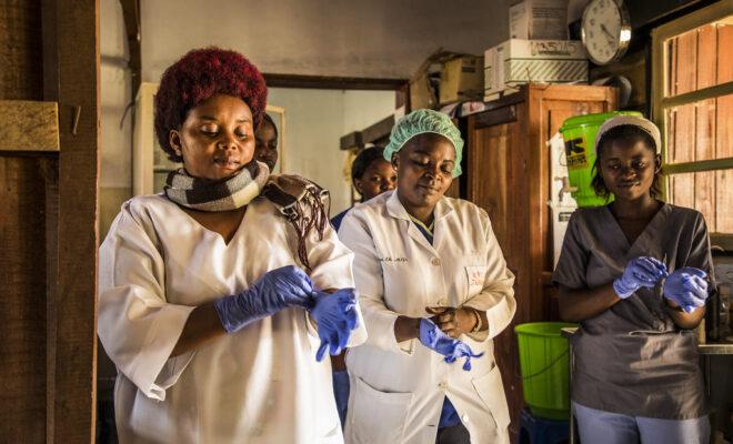 Abuja Declaration. Health workers in the DRC put on gloves on before checking patients at the hospital.