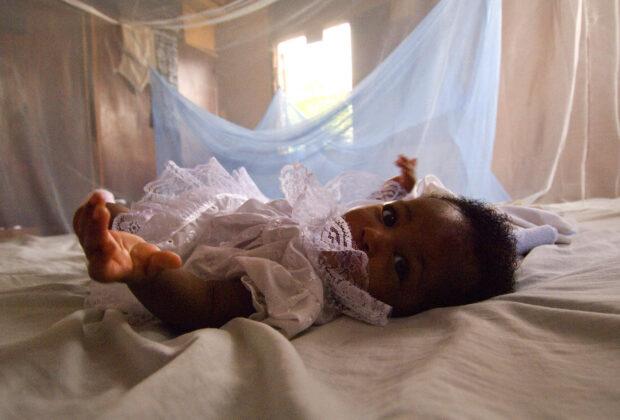 An infant surrounded by malaria bed net in Ghana. Credit: Arne Hoel / World Bank.