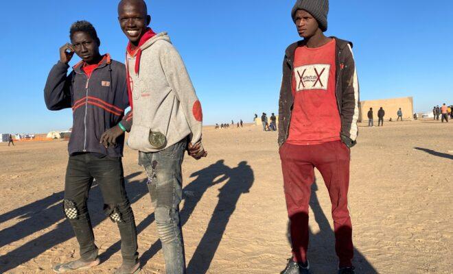 Three young men joke with each other to pass the time near the reception site in Assamaka, Niger, soon after being deported from Algeria. Because of COVID-19, all recently returned migrants are held here for a quarantine period of 14 days before being transported to Agadez. Credit: Mariama Diallo/MSF.