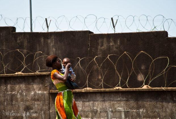 A woman and child walk past barbed wire in Freetown, Sierra Leone. Credit: Eduardo Fonseca Arraes.