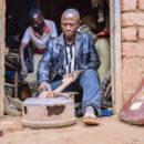 Moise Muhindo Kisuba builds a guitar at his workshop in Kirumba, south Lubero territory of the Democratic Republic of Congo. Behind him, Egide Kasereka Kighoma, an apprentice, works on a drum on July 15, 2021. Credit: Zita Amwanga/Global Press Journal.