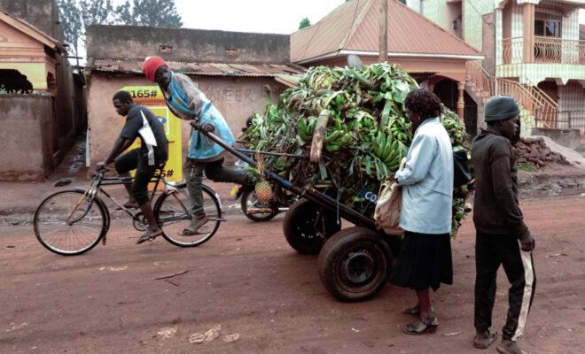 Middy Amule, a woman trader, jokes with a man while having the bananas she sells transported from Busia, Uganda, to Busia, Kenya.