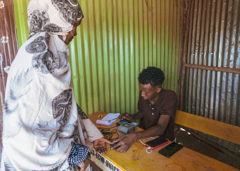 A woman gets her fingerprint read to access her cash transfer in Wado-Baris. Credit: Jaclynn Ashly.
