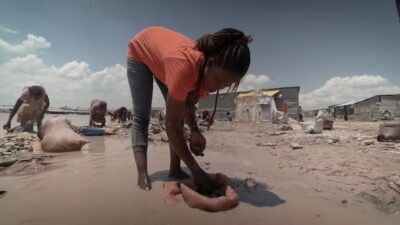 Mama Kalonda Alphonsine washes cobalt ore. Women are paid the equivalent of $3.75 for cleaning one full sack. Credit: Roy Maconachie.